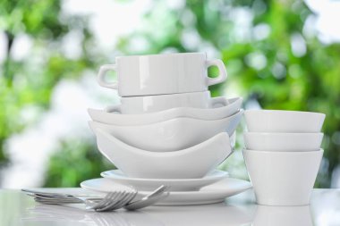 Bulanık yeşil arka planda beyaz masada farklı temiz tabaklar