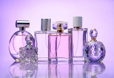 Ayna yüzeyinde soluk menekşe eğimli arka planda parfüm şişeleri