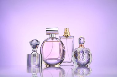 Ayna yüzeyinde menekşe eğimli arka plana karşı parfüm şişeleri