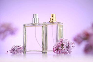 Ayna yüzeyindeki parfüm şişeleri ve leylak çiçekleri menekşe eğimli arka plan, seçici odak