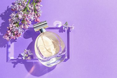 Düz kompozisyon, mor arka planda parfüm şişesi ve leylak çiçekleri vardı. Metin için boşluk