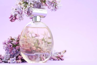 Parfüm şişesi ve mor arkaplanda leylak çiçekleri, yakın plan. Metin için boşluk