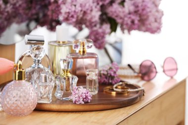 Parfümlü şişeler, leylak çiçekleri ve ahşap masa üzerindeki aksesuarlar, yakın plan.
