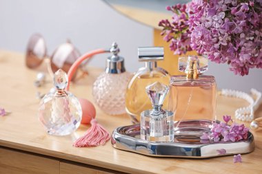 Parfüm şişeleri, aksesuarlar ve ahşap masada leylak çiçekleri.
