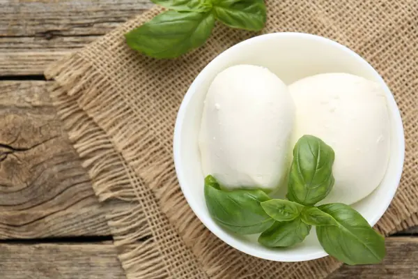 Ahşap masada lezzetli mozzarella peyniri ve fesleğen.