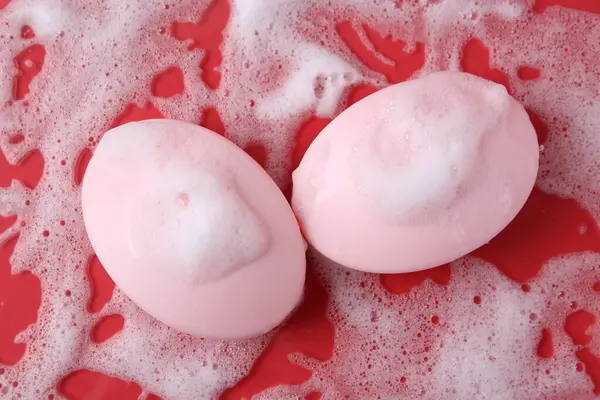 Kırmızı arka planda köpüklü sabun çubukları, düz yatış