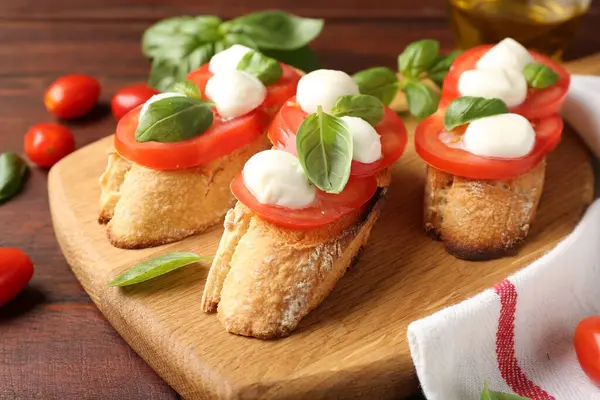 Mozarella peynirli, domatesli ve ahşap masadaki fesleğenli lezzetli sandviçler.