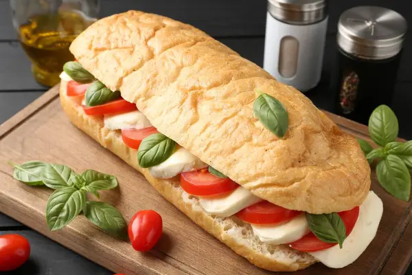 Mozarella peynirli, domatesli, fesleğenli, siyah ahşap masa, yakın plan.