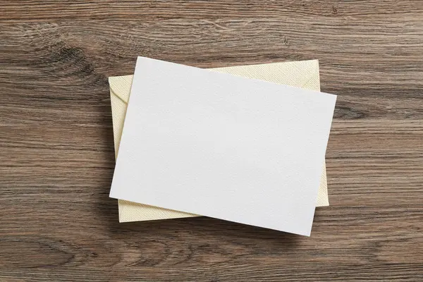 Boş davetiye kartı ve zarf ahşap masanın üstünde, üst tarafta. Tasarım için boşluk