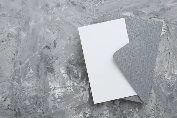 Gri desenli masa üzerinde boş davetiye ve zarf, üst manzara. Tasarım için boşluk