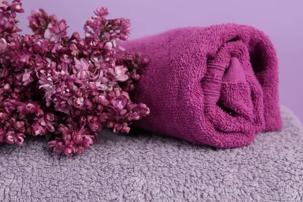 Yumuşak havlular ve mor arka planda leylak çiçekleri, yakın plan.