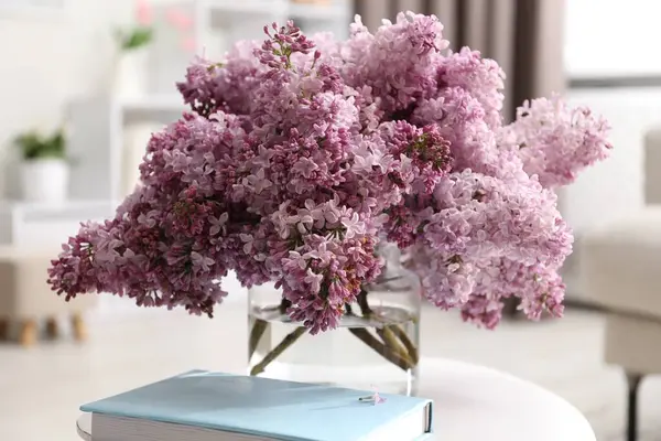 Vazodaki güzel leylak çiçekleri ve kapalı masadaki kitap, yakın plan.