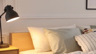 Odasında yumuşak çarşaflar olan rahat bir yatak, kamera sağa hareket ediyor. Ev tekstili