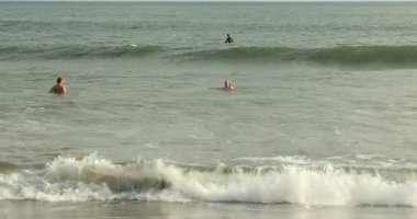 Bali, Endonezya - 20 Mayıs 2025: İnsanlar denizde yüzüyor ve insanlar plaj boyunca koşuyor