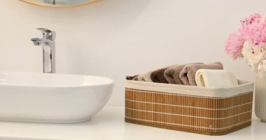 Depoda yumuşak havlular, şakayık çiçekleri ve kozmetik ürünleri kapalı alanda, kamera sağa hareket ediyor.