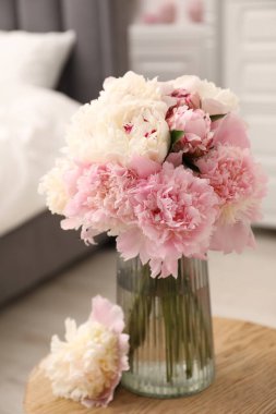 İçerideki ahşap masada vazodaki güzel şakayıklar.