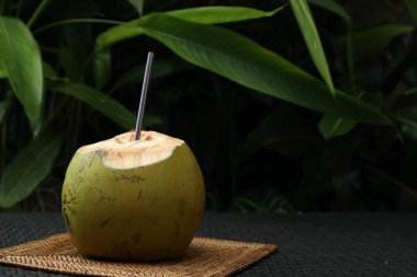 Yeşil hindistan cevizi, ferahlatıcı içecek ve hasır hasır masa üzerinde saman, yakın plan. Metin için boşluk