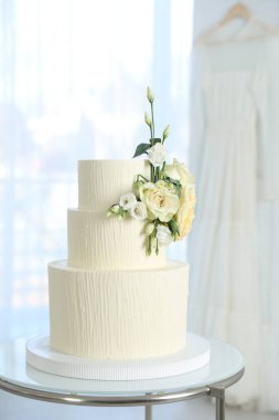 İçerideki masada çiçeklerle süslenmiş nefis düğün pastası.