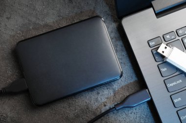 USB flaş bellek, sabit disk kablo ve laptop ile koyu gri masa, düz yatıyordu