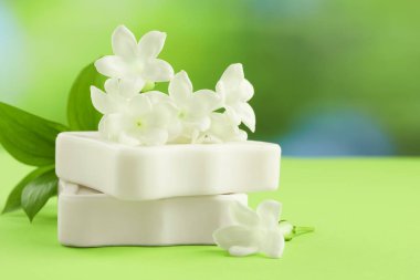 Açık yeşil masada sabun ve yasemin çiçekleri bulanık arka planda, yakın planda