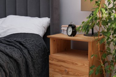 İçinde lamba, çalar saat ve yatağın yanında kitaplar olan komodin. İç tasarım