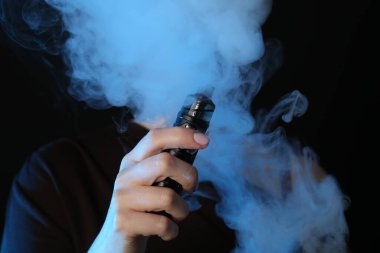 Siyah arka planda neon ışıkları altında elektronik sigara içen kadın