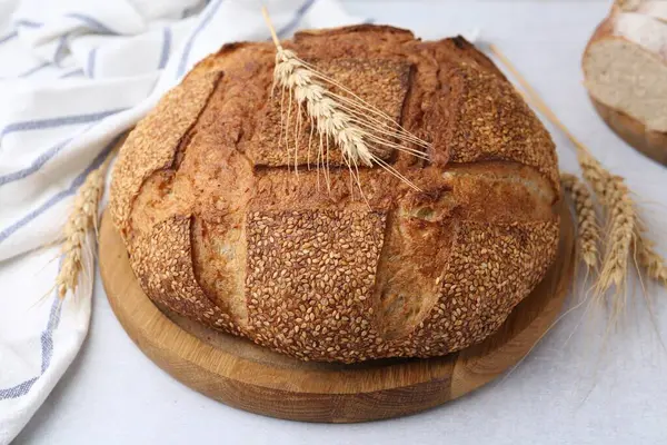 Taze pişmiş ekmek, susam tohumları ve açık gri masada çiviler, yakın plan.