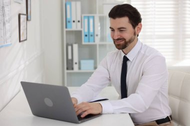 Hastanedeki beyaz masada dizüstü bilgisayarla çalışan profesyonel bir doktor.