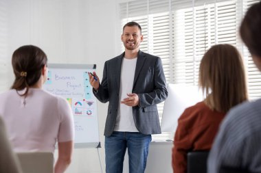 İçerde seyirci önünde konuşma yapan adam.