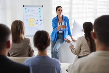 Kadın içeride seyirci önünde konuşma yapıyor.