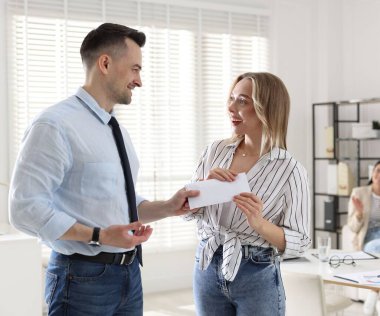 Para bonusu. Patron ofisteki çalışana zarf veriyor.