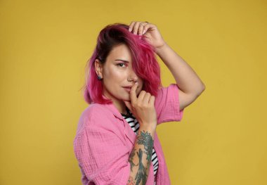 Sarı arka planda pembe boyalı saçlı güzel bir kadın.