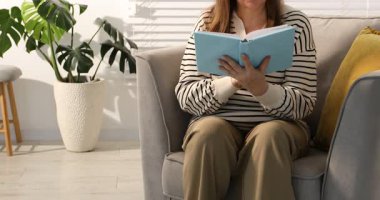 Görme sorunu olan bir kadın evdeki koltukta kitap okuyor, kamera yukarı çıkıyor.