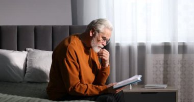 Görme sorunu olan son sınıf öğrencisi evde yatağında kitap okuyor.