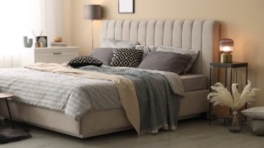 Odasında yumuşak çarşaflar ve battaniyeler olan rahat bir yatak, sola hareket eden kamera. Ev tekstili