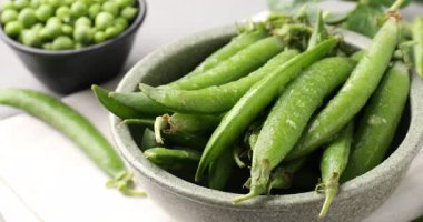 Gri masada taze taze taze bezelyeler, yakın plan. Kamera sağa hareket ediyor