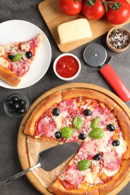 Lezzetli pizza ve malzemeler gri masada, düz yatıyordu.