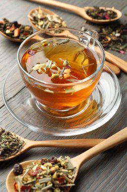 Cam bardakta Aromatik bitki çayı ve ahşap masada kuru yapraklar, yakın plan.