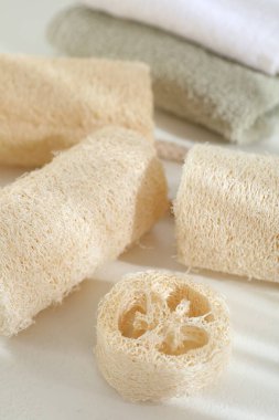 Beyaz masada farklı banyo süngeri ve havlular, yakın plan.