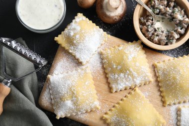 Pişmemiş ravioli, mantar ve sos siyah masada, düz yatıyordu.