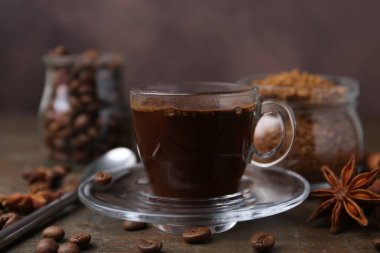 Bir fincan aromatik kahve, fasulye, hazır toz ve baharatlar ahşap masada, yakın plan.