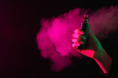 Siyah arka planda neon ışıklarda elektronik sigara içen bir kadın, yakın plan. Metin için boşluk