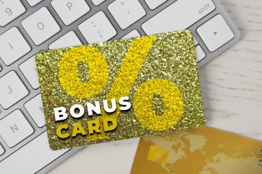 Beyaz ahşap masa üzerinde şık tasarım ve bilgisayar klavyeli bonus kart, üst görünüm