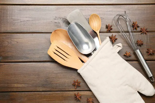 Fırın eldiveninde farklı mutfak aletleri ve ahşap masada anason yıldızları.