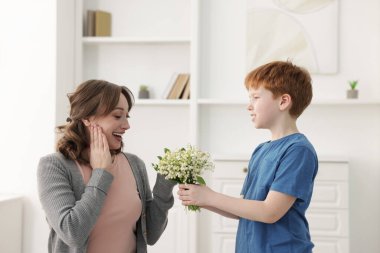Çocuk, evde güzel bir buket çiçekle annesine sürpriz yapıyor.