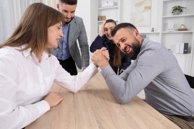 İş adamları, ofisteki tahta masada bilek güreşi yapıyorlar.