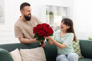 Evinde sevgili karısına bir buket kırmızı gül sunan adam.