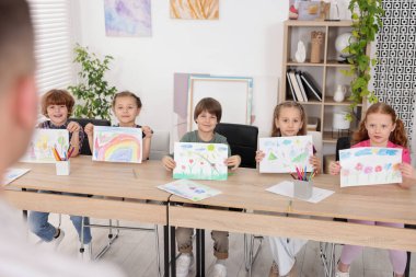 Çocuklar resim dersinde öğretmenlerine resimlerini gösteriyorlar, seçici bir şekilde.