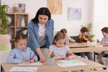 Çocuklara resim yapmayı öğreten kadın kapalı alanda resim dersi veriyor, seçici bir odak.
