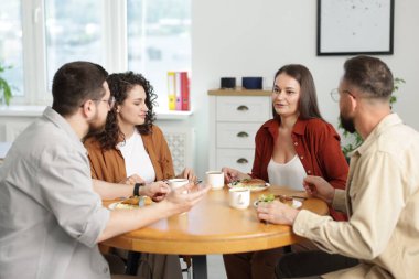 İş arkadaşları öğle arasında ofiste sohbet ediyorlar.